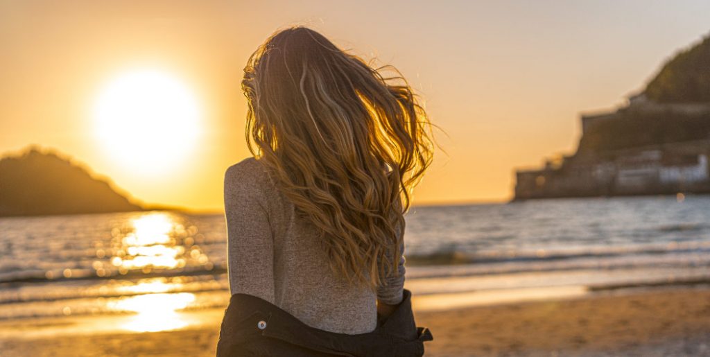 mujer rubia de espaldas en la playa